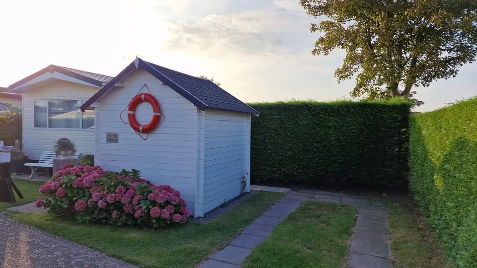Gartenhaus mit Rettungsring und blühenden Hortensien