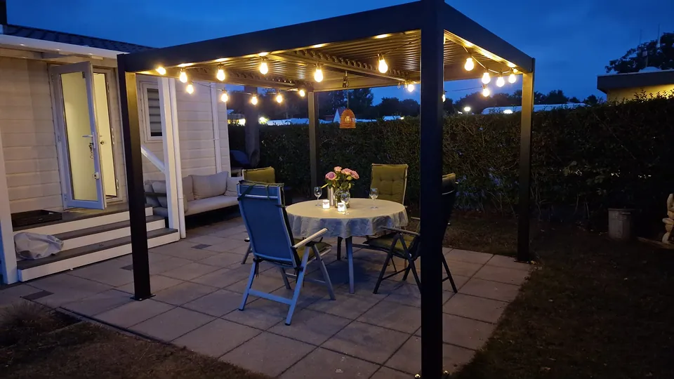 Lamellen-Pergola mit Lichterkette zur blauen Stunde vor dem Chalet Zandput in Renesse