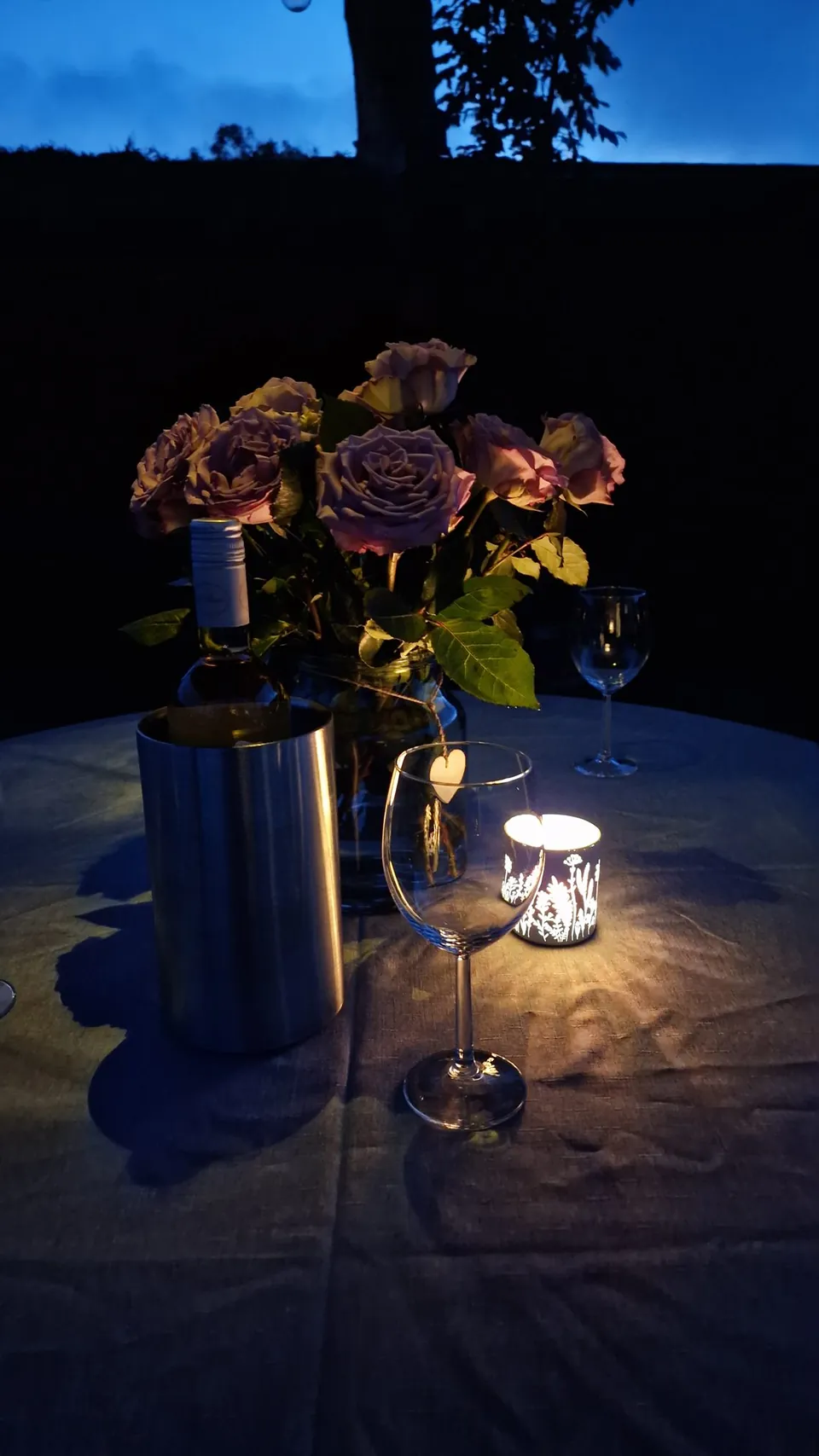 Rosen, Weinglas und Windlicht auf dem Terrassentisch